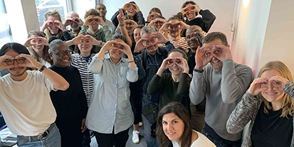 Groupe de personnes souriantes mimant avec leurs mains des lunettes de réalité virtuelle